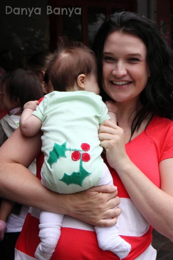 Danya Banya holding 3 month old baby Bee wearing Christmas onesie with holly on the bottom