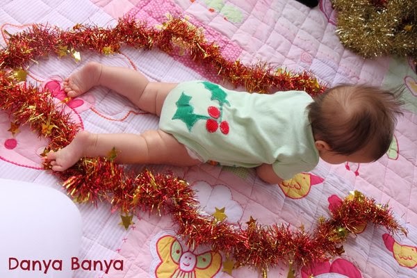 Baby wearing onesie with Christmas holly appliqued on bottom