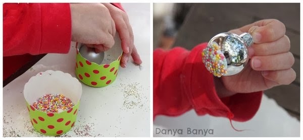 Playing with food! Decorating Christmas decorations with sprinkles.